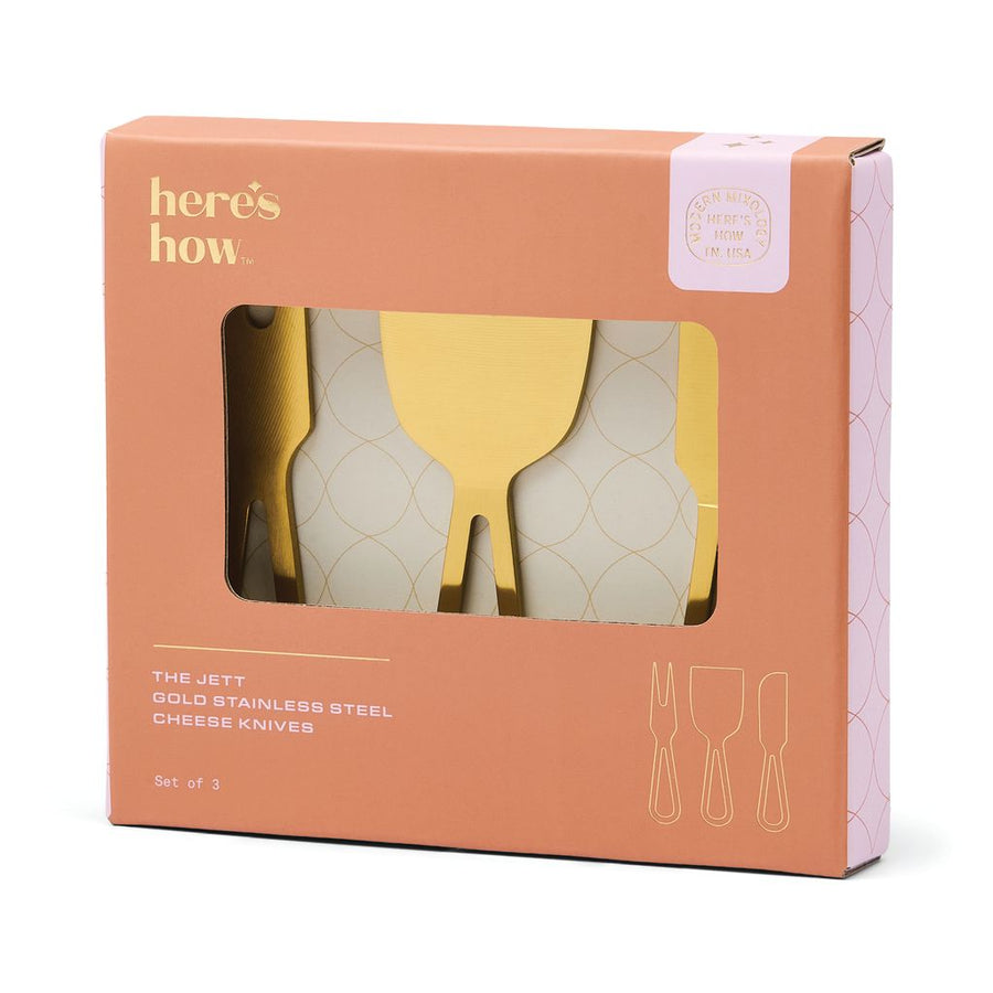 Gold cheese knives set in a box on a white backgound