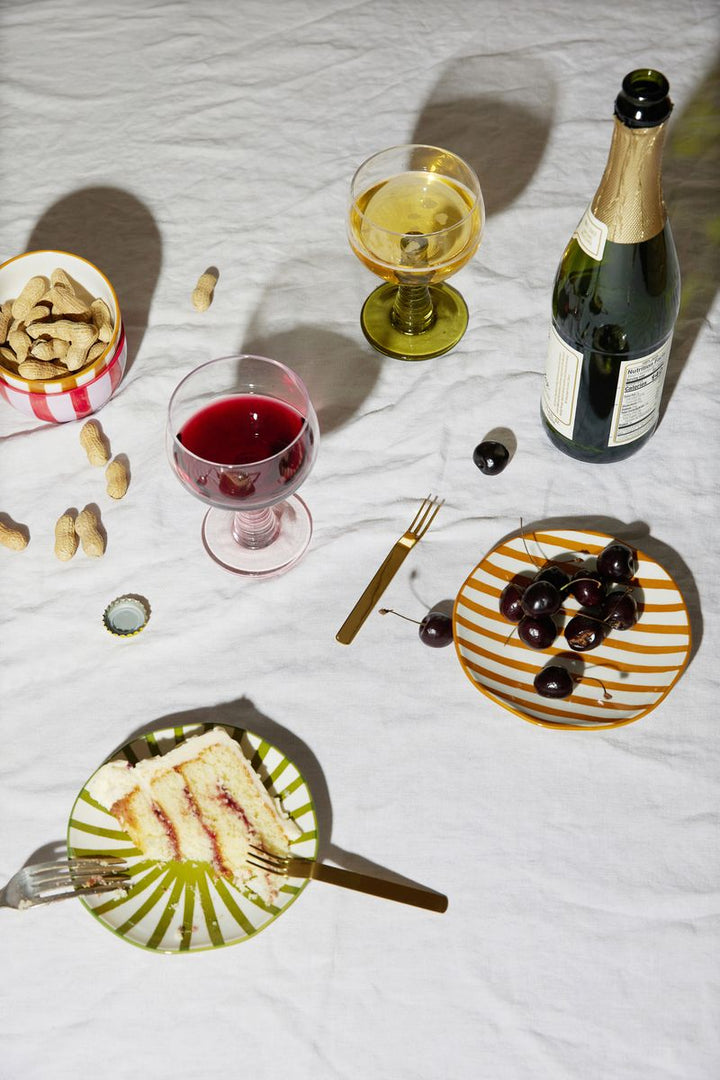 Plates. wine glasses, bottle of wine on a table with a white tablecloth