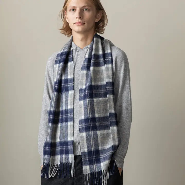 Man wearing a blue and gray plaid scarf against a beige background