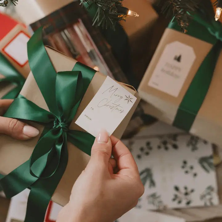 Gift box with green ribbon and 'Merry Christmas' tag, surrounded by other wrapped gifts.