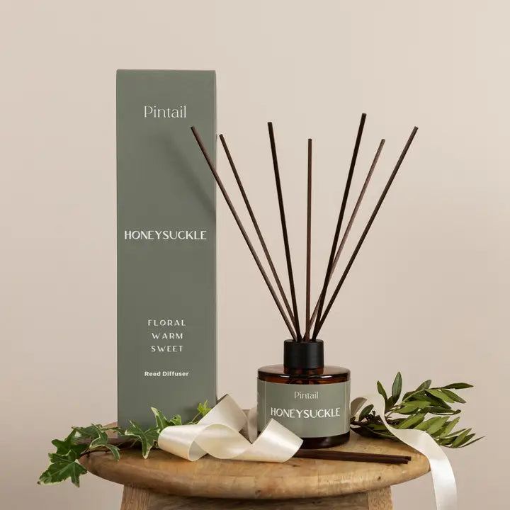 Pintail Honeysuckle reed diffuser with packaging on a wooden stand.