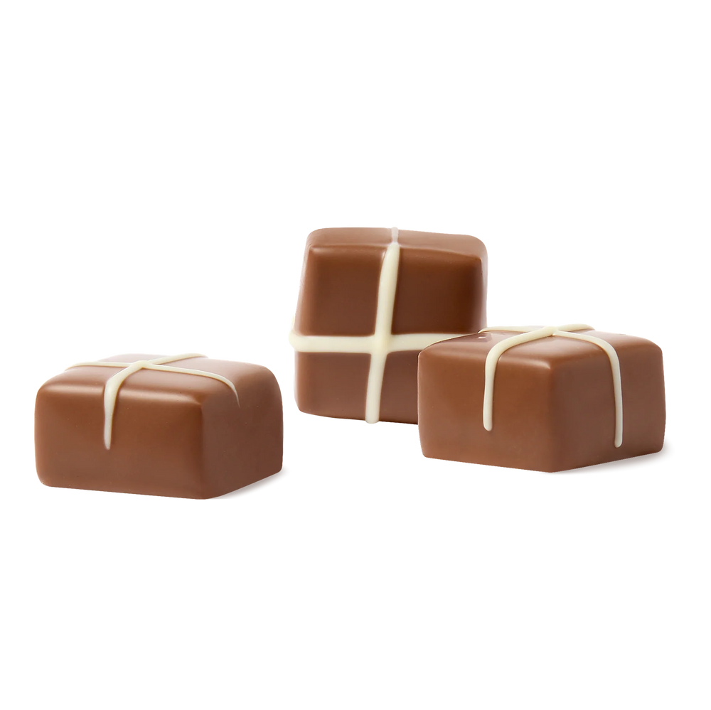 Three square-shaped chocolates with white drizzle on a white background