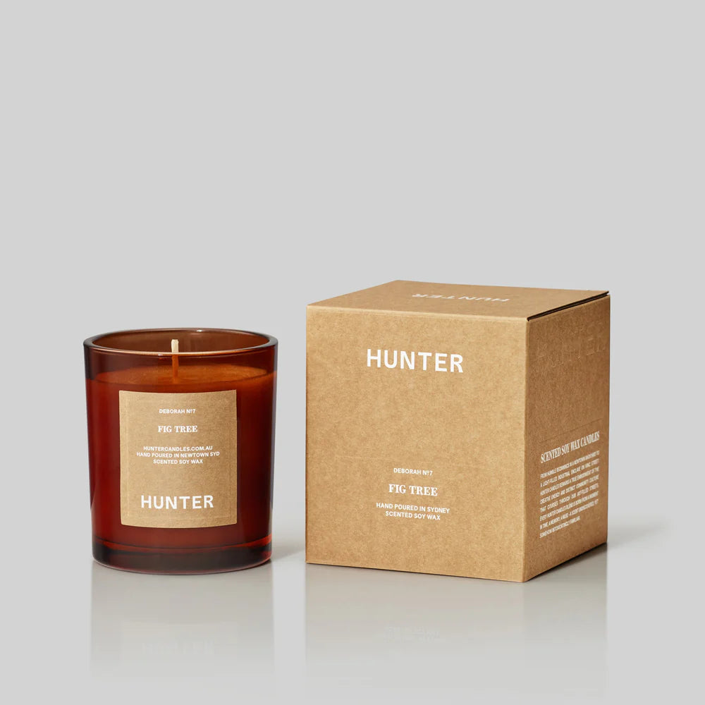 Candle labeled 'Hunter' with its packaging on a light gray background