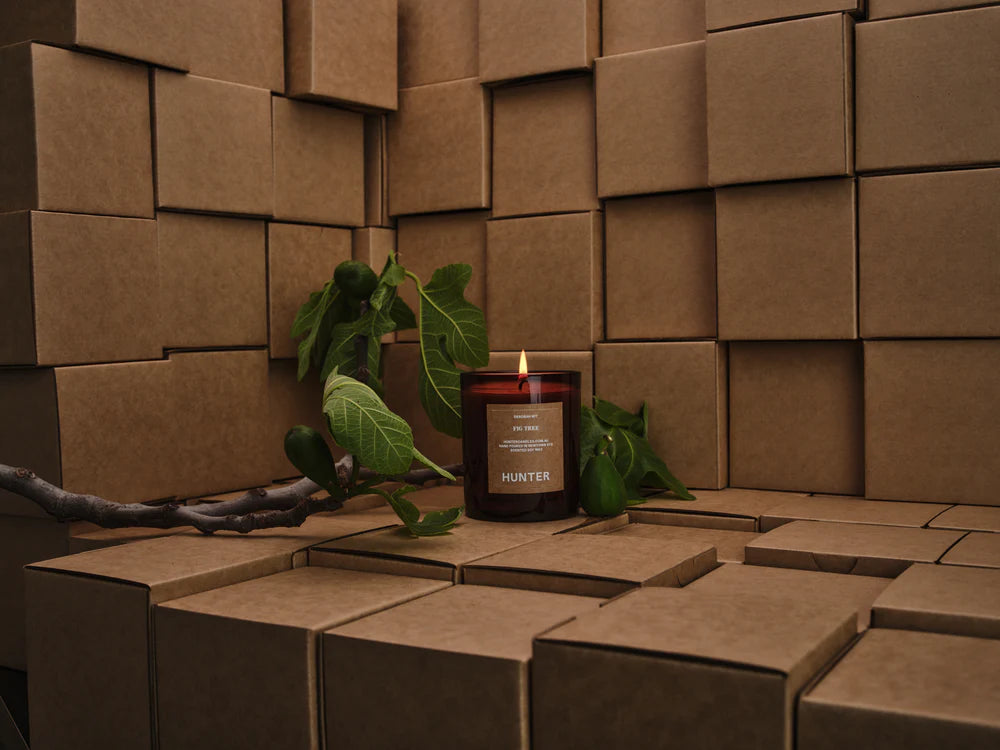 Candle with a leafy branch on a textured brown surface
