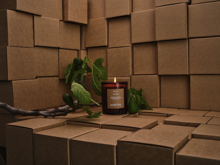 Candle with a leafy branch on a textured brown surface