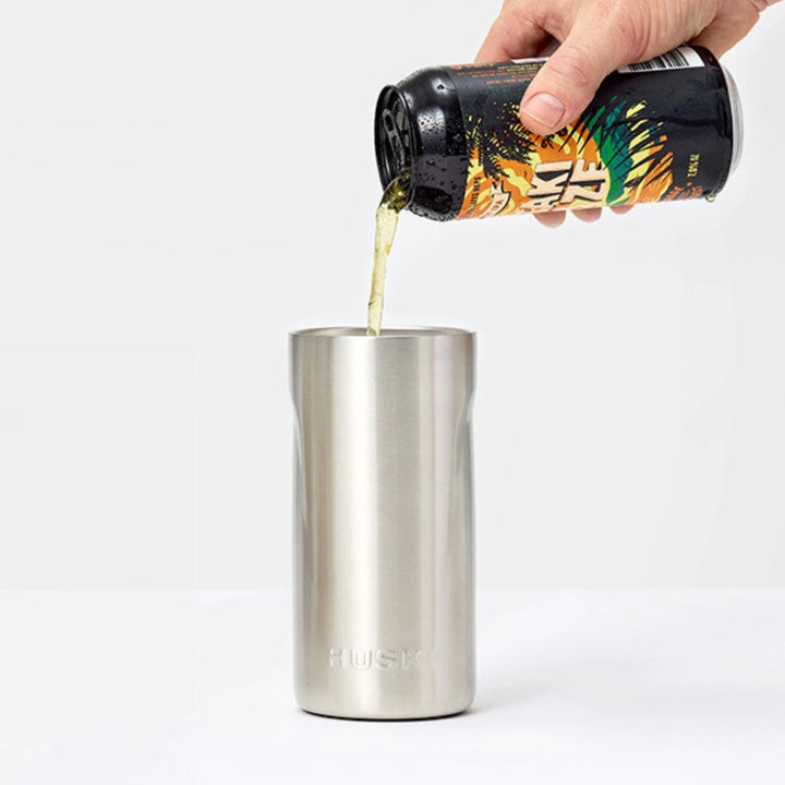Person pouring a drink from a colorful bottle into a stainless steel tumbler on a white background