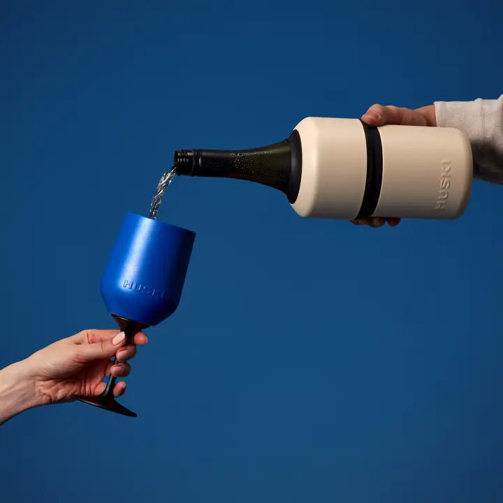 Person pouring liquid from a beige bottle into a blue cup against a blue background