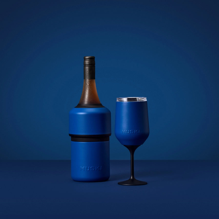 Blue wine bottle cooler and glass on a blue background