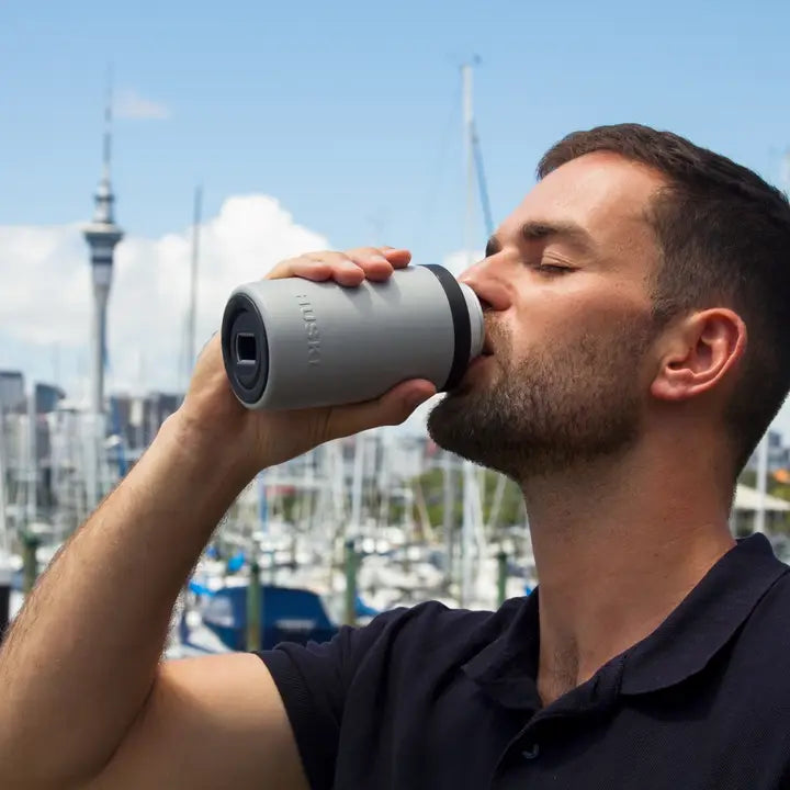 Man drinking from a Yeti water bottle with a cityscape in the background