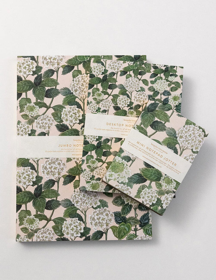Set of floral notebooks with green leaves and white flowers on a light gray background