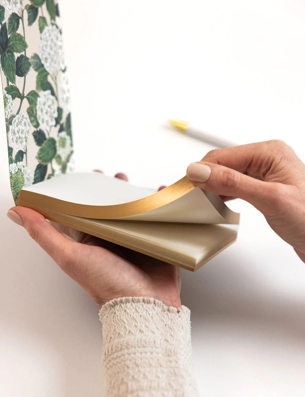 Person holding a notebook with a floral pattern on the cover
