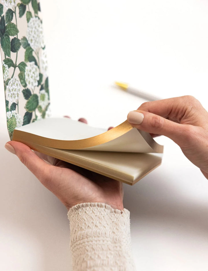 Person holding a notebook with a floral pattern on the cover