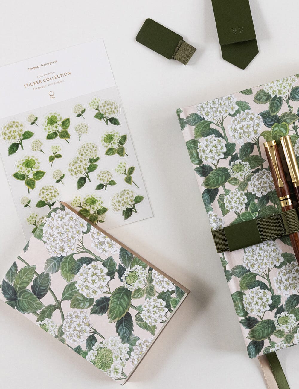 Notebooks with floral design and green ribbons on a white background