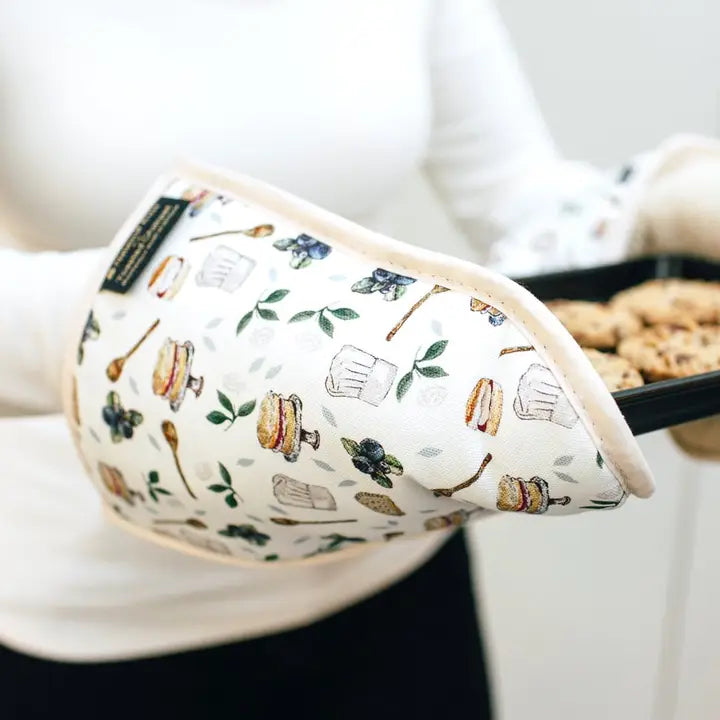 Patterned oven glove with kitchen-themed design on a white surface