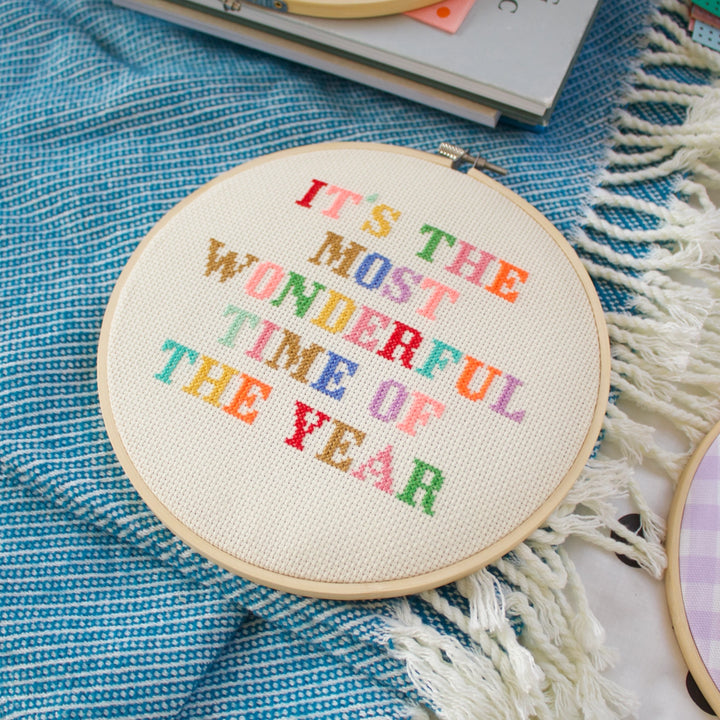 Embroidery hoop with colorful text on a blue fabric background
