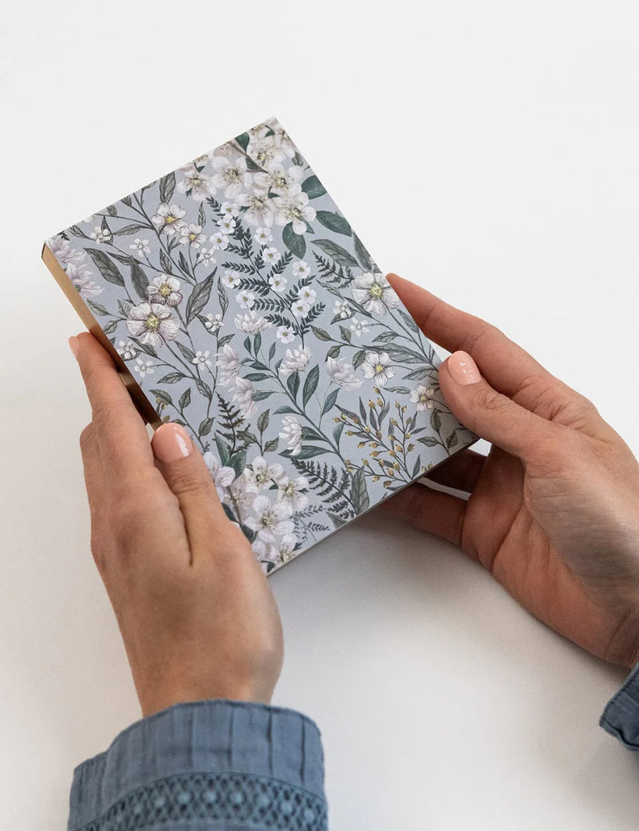 Person holding a small notebook with floral design on a white background