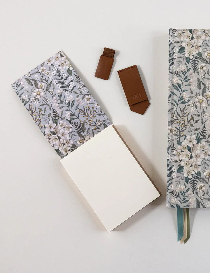 Floral-patterned notebook and white notebook on a light gray background