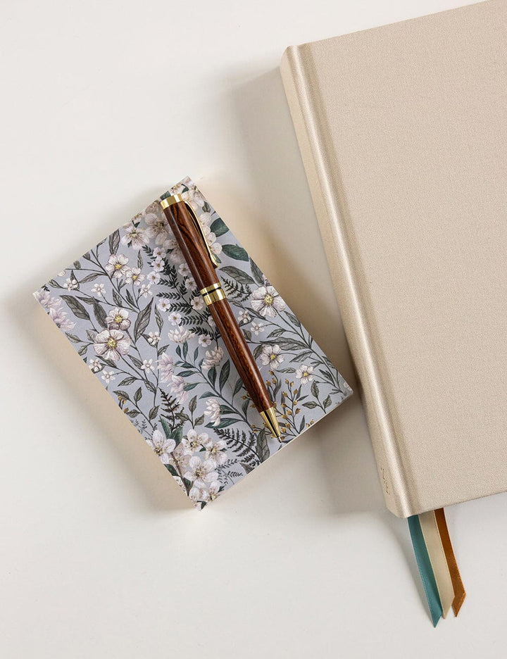 Floral notebook and pen on a light surface