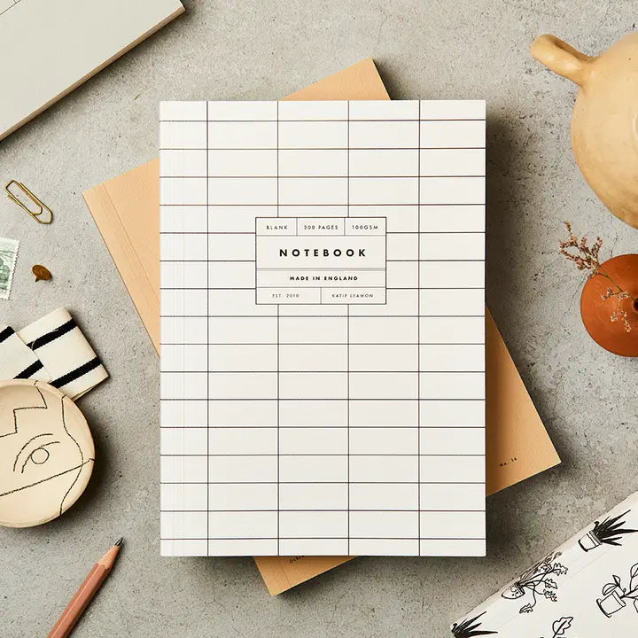 Grid notebook on a textured surface with stationery items