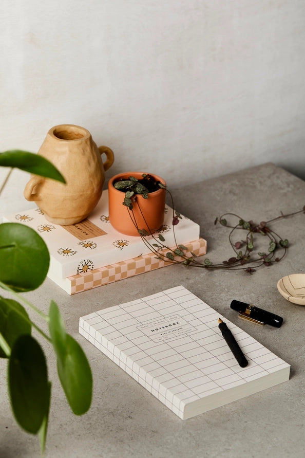 Notebook with grid pattern, pen, and decorative items on a textured surface.