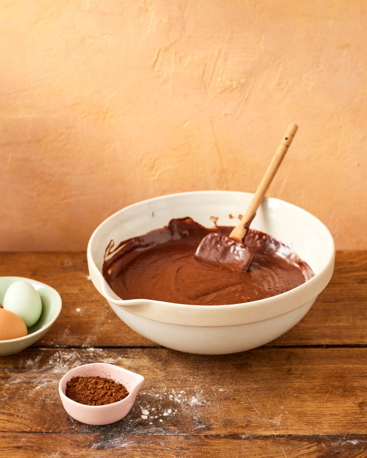 Bowl of chocolate batter with a spatula on a wooden table