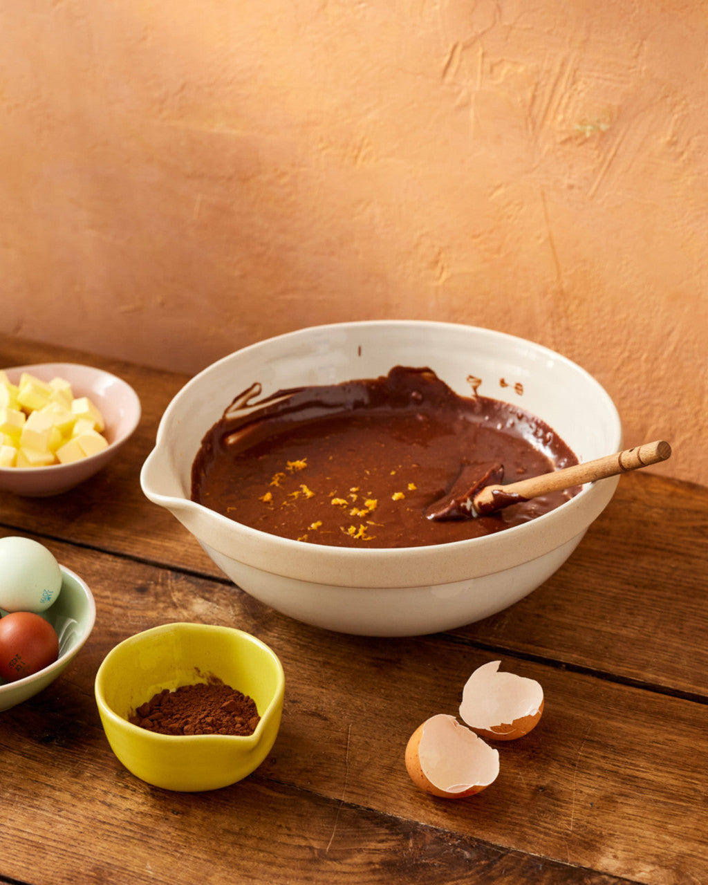 Bowl of chocolate mixture on a wooden table with ingredients around
