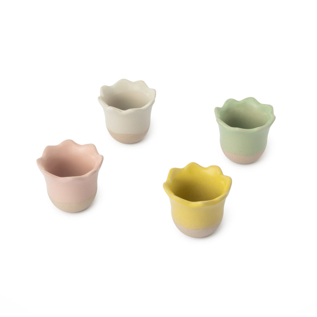 Set of four colorful ceramic egg cups with wavy edges on a white background