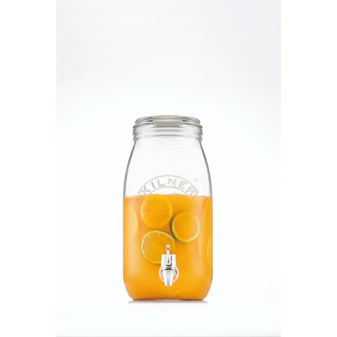 Clear glass drink dispenser filled with orange juice on a white background