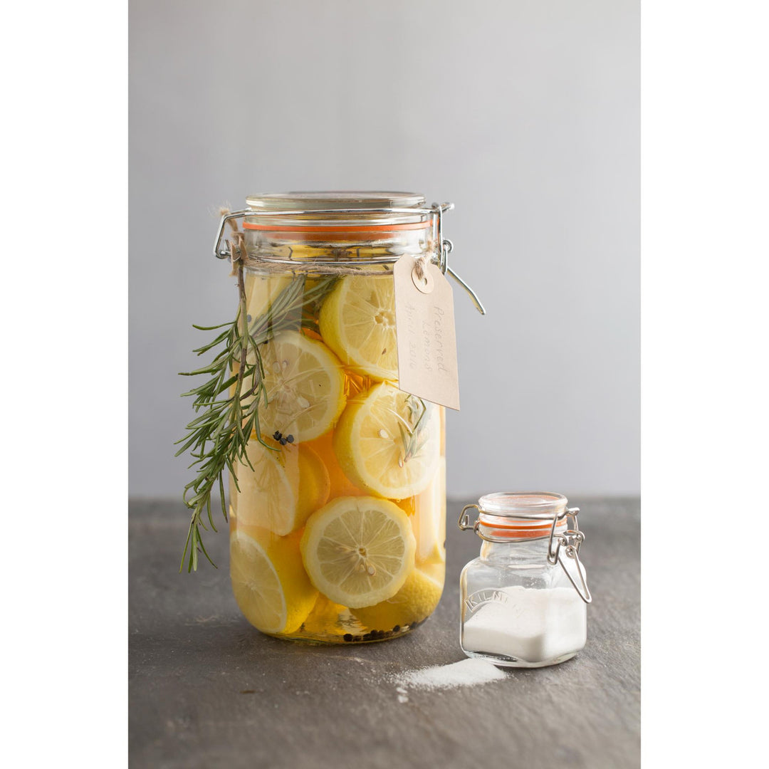 Glass jar with lemon slices and rosemary on a gray surface