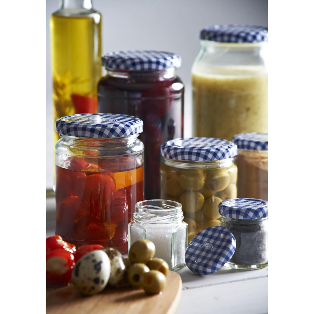 Assorted jars with pickled vegetables and condiments on a wooden board.