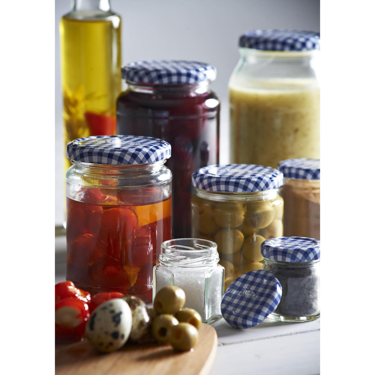 Assorted jars with pickled vegetables and condiments on a wooden board.