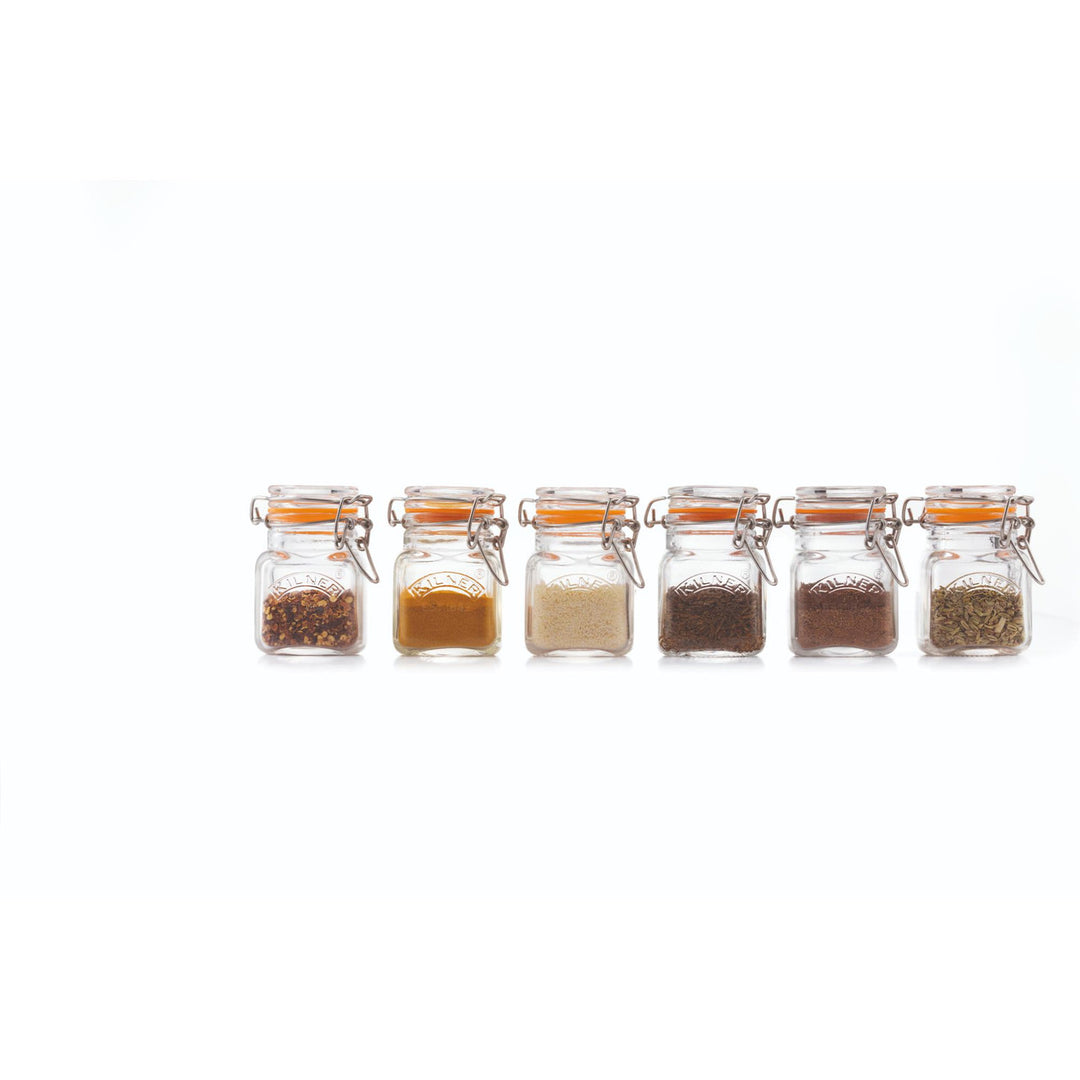 Set of six small glass jars with different spices on a white background