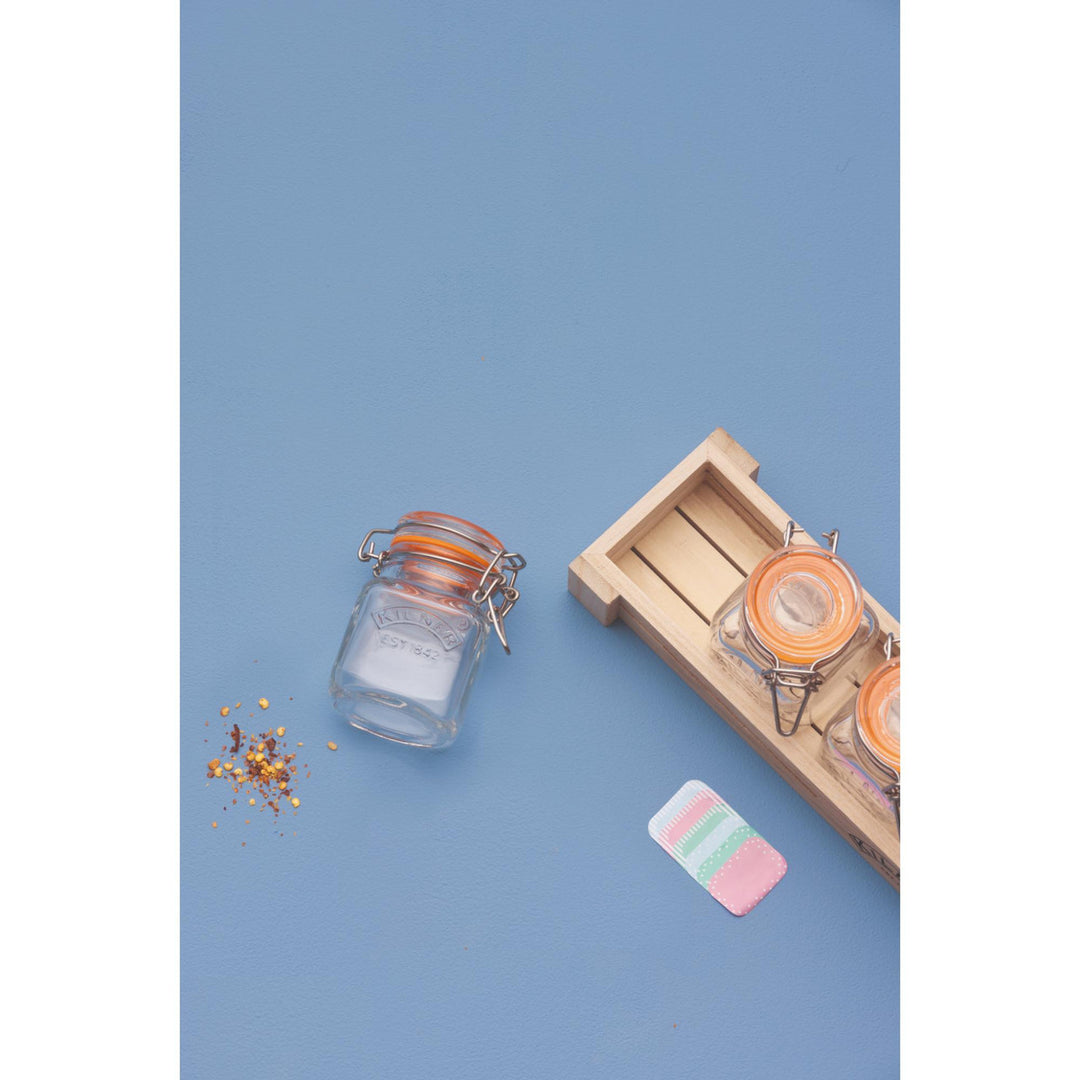 Small glass jar with a wooden tray on a blue background