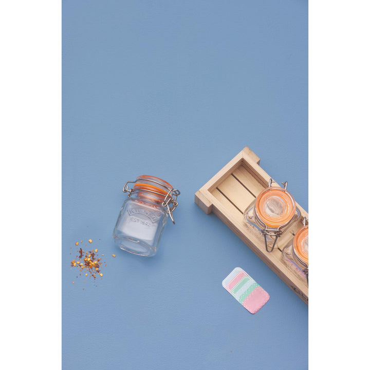 Small glass jar with a wooden tray on a blue background