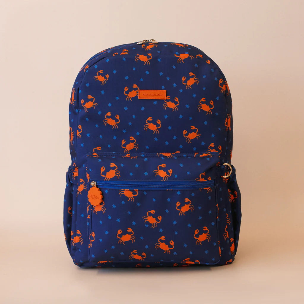 Blue backpack with orange crab pattern on a beige background