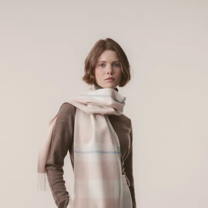 Woman wearing a large plaid scarf on a plain background