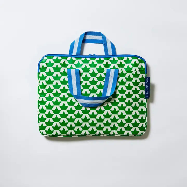 Green and white patterned bag with blue handles on a light gray background
