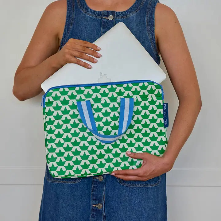 Person holding a green and white patterned laptop sleeve with blue accents.
