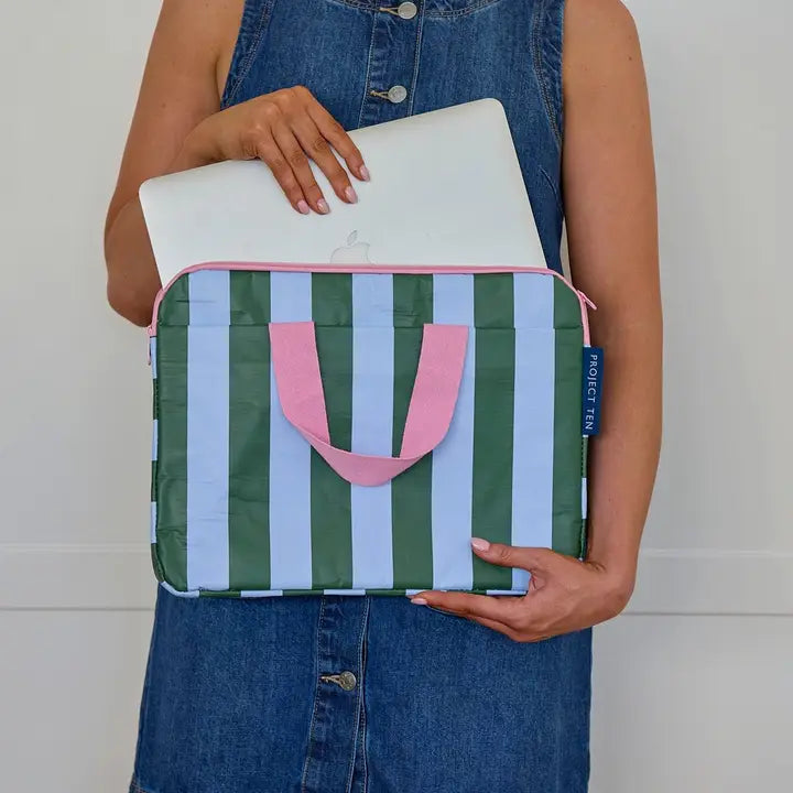 Person holding a striped bag with a laptop inside, wearing a denim outfit.