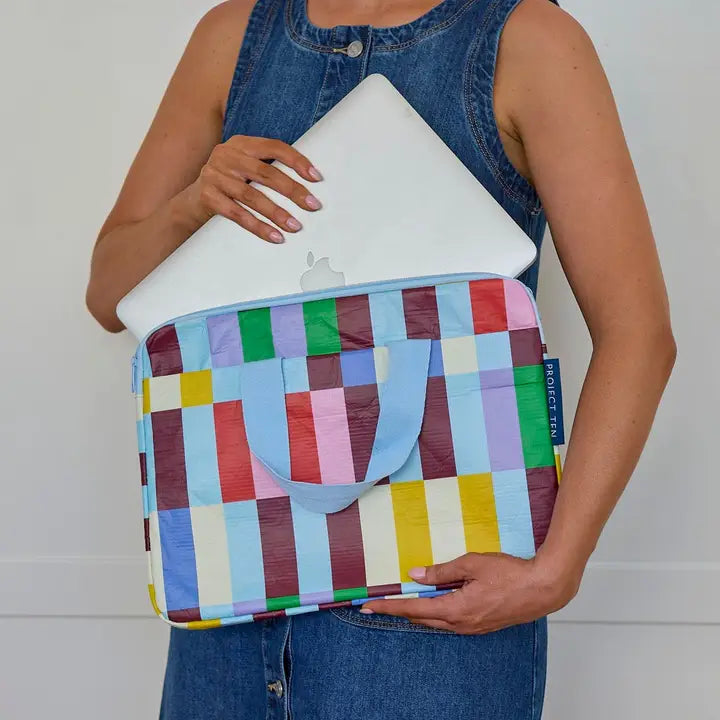 Person holding a colorful striped laptop sleeve against a white background