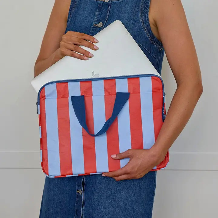 Person holding a red, white, and blue striped bag with a plain background