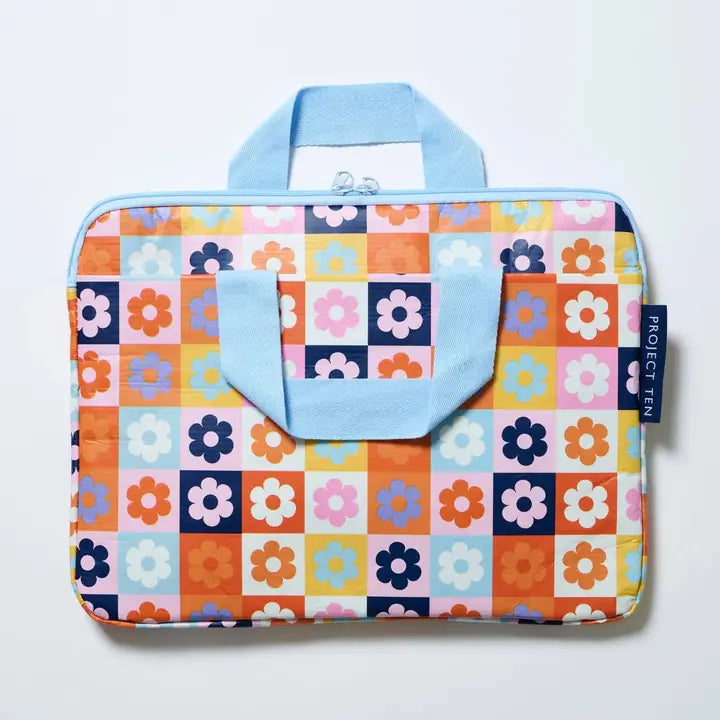 Colorful floral and checkered patterned bag with a blue handle on a light gray background