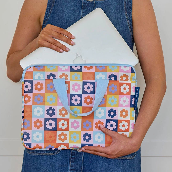 Person holding a colorful floral laptop sleeve with a plain background