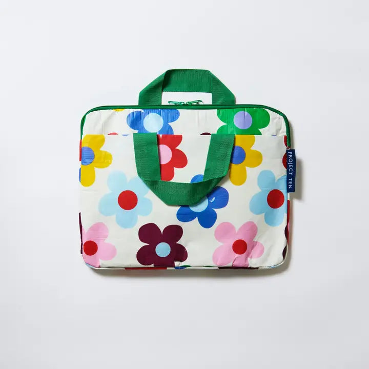 Floral-patterned bag with green handles on a white background