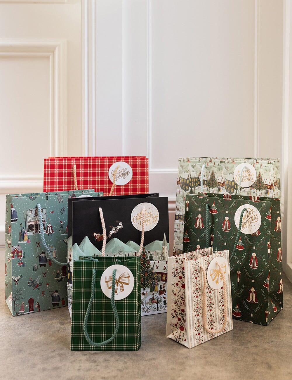 Collection of Christmas-themed gift bags on a neutral background