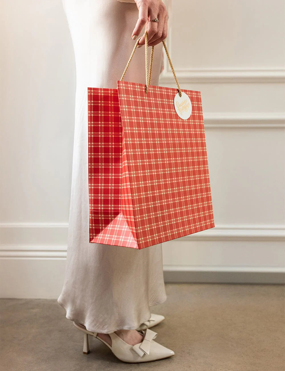 Person holding a red plaid gift bag with a white background