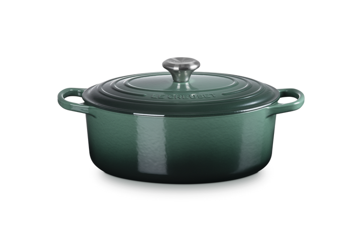 Green enameled cast iron Dutch oven with a lid on a white background