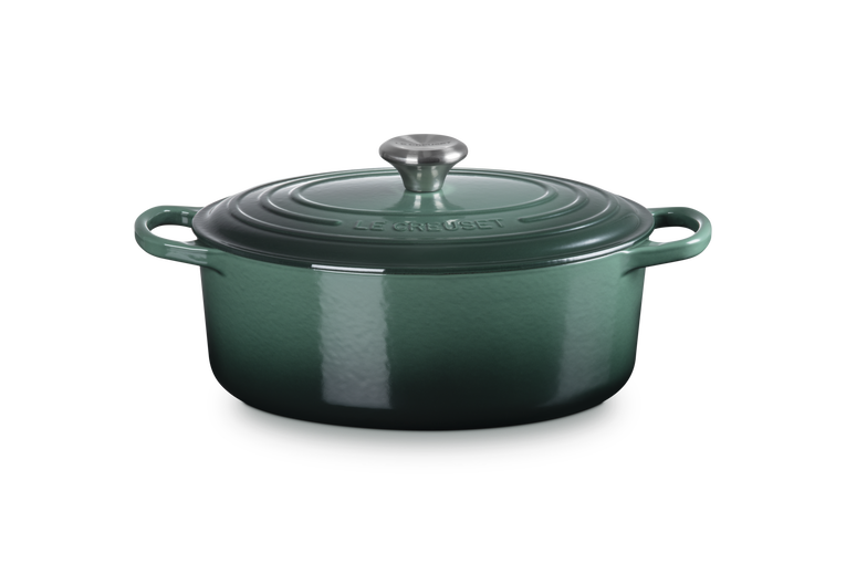 Green enameled cast iron Dutch oven with a lid on a white background