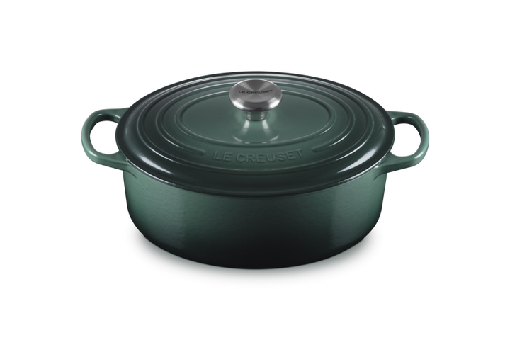 Green cast iron cookware pot with lid on a white background