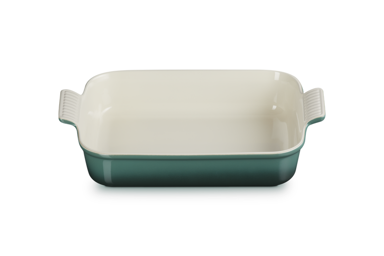 Rectangular ceramic baking dish with green base and white top on a white background